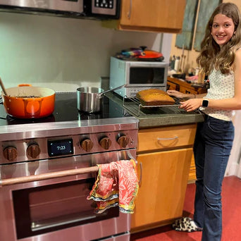 Teenage girl proudly shows off her pumpkin bread she made with her Charlie battery-powered induction stove with black walnut knobs made by Copper. 