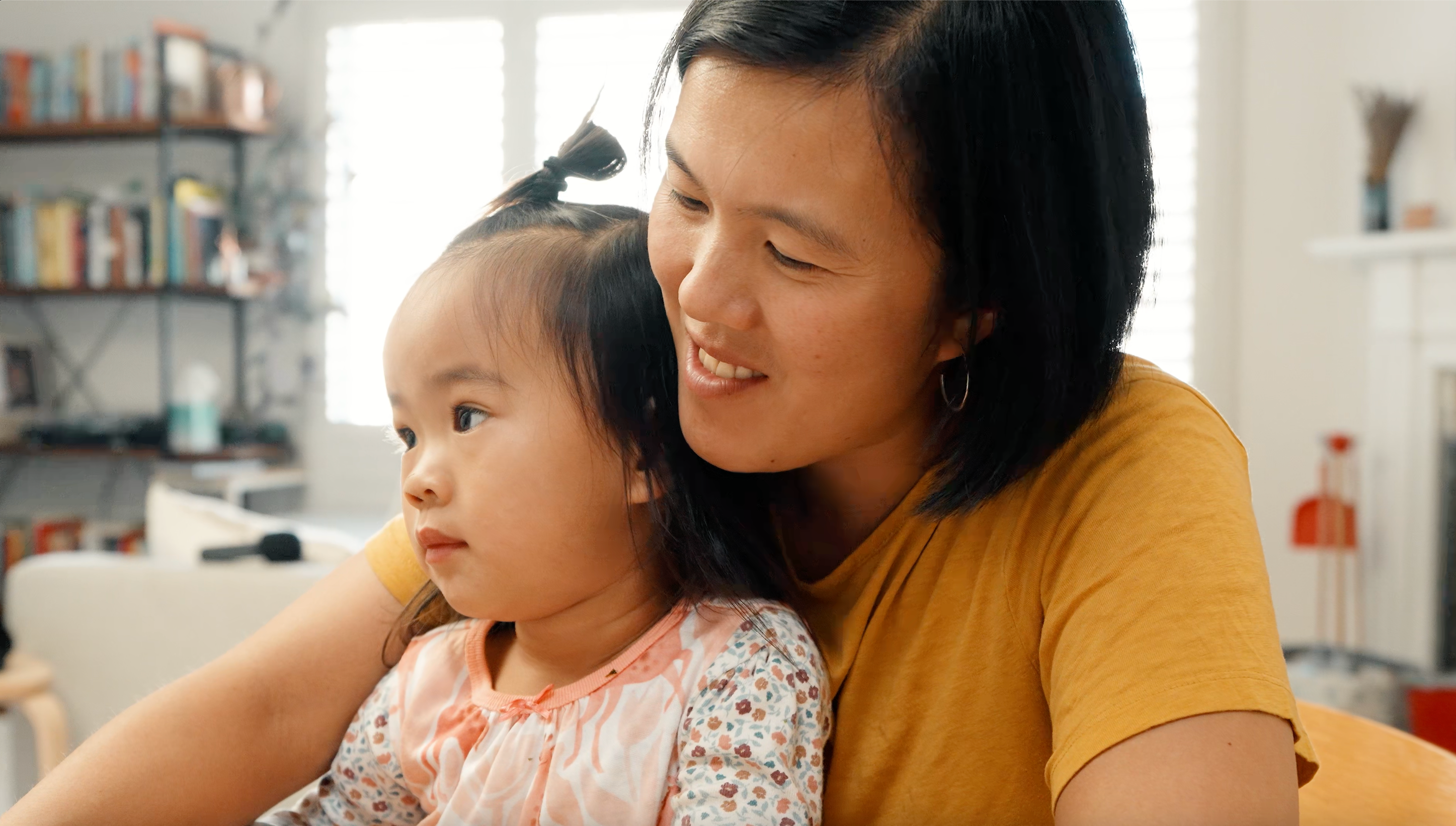 Load video: Woman wearing a yellow t-shirt with short black hair and a toddler on her lap 